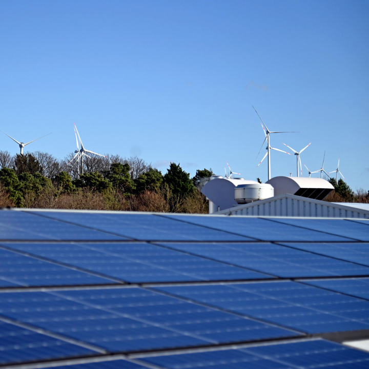 Solarmodule auf dem Dach und im Hintergrund Windräder